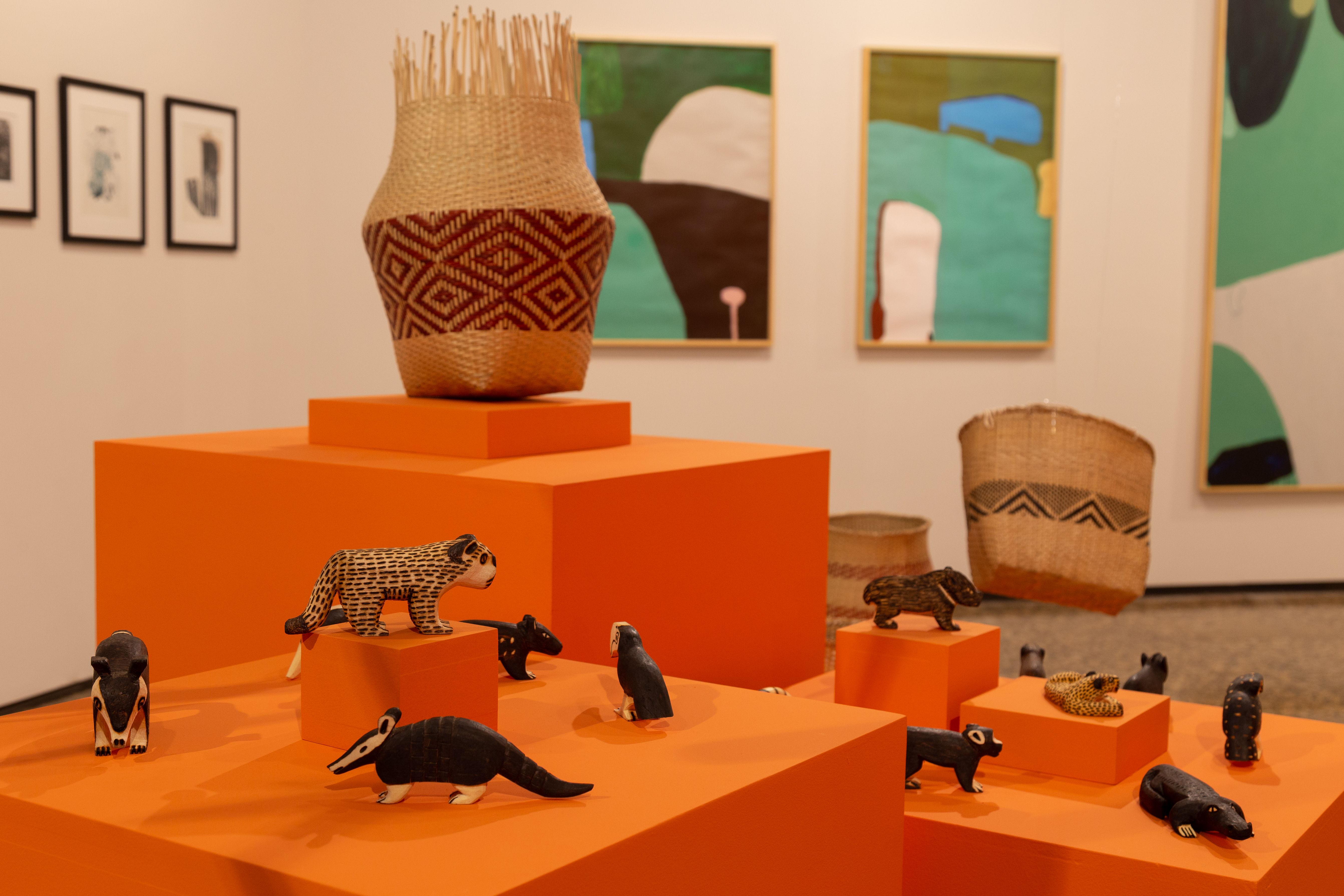 Cestarias e miniaturas em madeira de animais silvestres em pedestais expositivos -  modelo cubo na cor laranja.