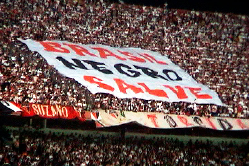 Reprodução de cena do média-metragem "Zumbi Somos Nós - O Documentário", que destaca bandeira com as palavras BRASIL NEGRO SALVE.