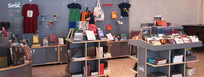 Foto da Loja Sesc na Unidade de Santo Amaro com mobiliário cinza e produtos (livros, camisetas e CDs) à venda