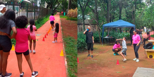 A imagem é dividida em duas partes: À esquerda: Um grupo de crianças e adultos está em uma pista ao ar livre com cones coloridos (vermelho, laranja e amarelo) dispostos em zigue-zague. Uma mulher de camiseta rosa está conduzindo a atividade. As pessoas estão organizadas em fila, observando. À direita: A cena ocorre em uma área de terra batida, com árvores ao fundo e uma tenda azul. Um homem segura uma bola azul junto ao pescoço, posicionado para arremessar. Perto dele, um menino está agachado com os braços projetados para frente, acompanhado por duas mulheres usando camisetas rosas.