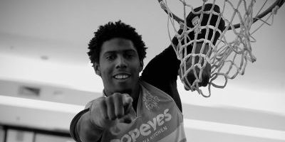 Foto em preto e branco do Gustavo Haakin enterrando a bola de basquete.